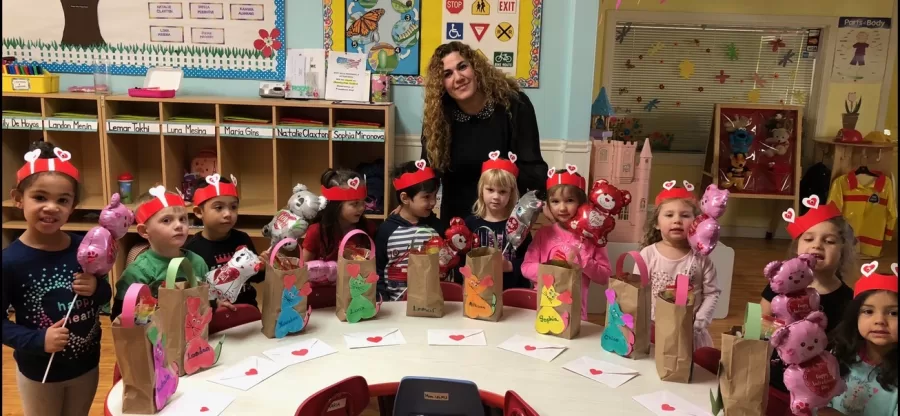 A teacher and her preschool class show off the Valentine bags they made at the round craft table